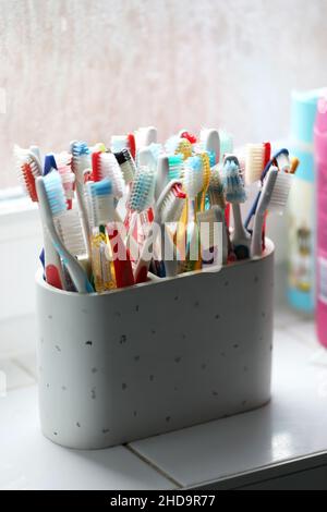 Une sélection de brosses à dents en plastique colorées dans un pot dans une salle de bains à Chichester, West Sussex, Royaume-Uni. Banque D'Images