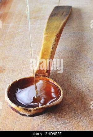 Miel frais naturel biologique versé dans une cuillère en bois. Banque D'Images