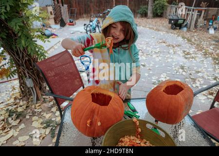 Une jeune fille ramasse des graines de citrouille le jour de l'automne Banque D'Images