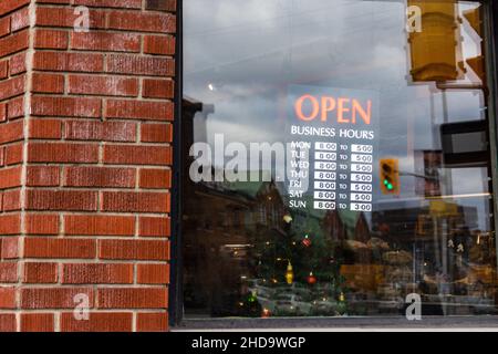 Affiche des heures d'ouverture sur la fenêtre du magasin au centre-ville avec arbre de Noël et reflet de la rue à Ottawa, Canada Banque D'Images