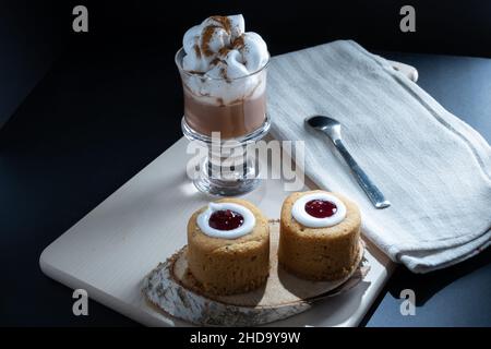 Helsinki / Finlande - 4 JANVIER 2022: Aliments traditionnels finlandais: Gros plan de la torte de Runeberg avec garniture de framboise.Une tasse de chocolat chaud sur le côté. Banque D'Images