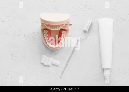 Tube avec pâte dentaire, pinceau, gommes à mâcher et modèle de mâchoire sur fond clair Banque D'Images