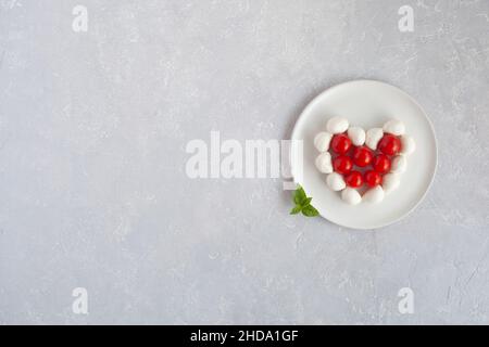 Tomates cerises et mozzarella en forme de coeur, concept de cuisine facile pour la Saint-Valentin, vue du dessus, espace copie Banque D'Images