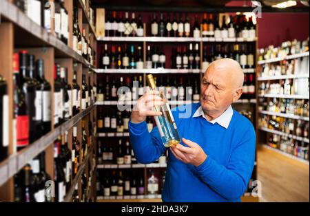 le pensionné choisit le vin blanc dans un magasin de spiritueux Banque D'Images