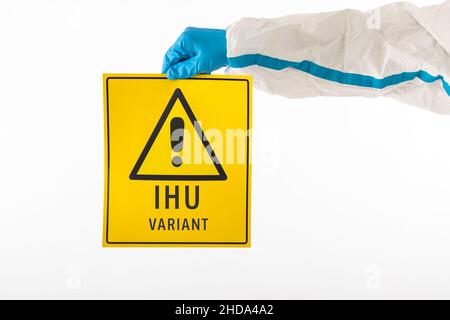 Détail d'un bras d'une infirmière médicale portant un EPI et des gants en latex avec un signe jaune avec un symbole de danger qui se lit comme suit : ''variante IHU''.Coronavirus, p Banque D'Images