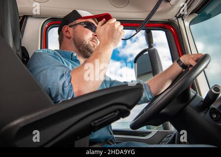 Semi-conducteur de camion parlant sur la radio CB tout en conduisant dans un semi-remorque moderne.Thème de l'industrie du transport. Banque D'Images