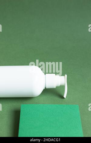 Bouteille blanche pour crème de soin de la peau, shampooing, après-shampooing sur fond vert. Espace de copie Banque D'Images