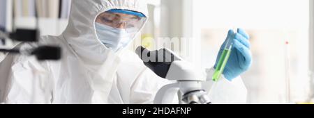 Femme chimiste en costume de protection conduit des recherches de laboratoire sur le liquide vert Banque D'Images