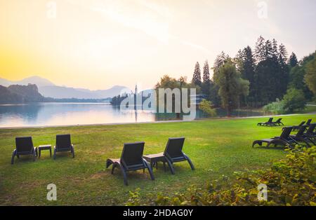 De nombreux fauteuils sur l'herbe sans personne au bord du lac de Bled en Slovénie pendant la matinée nature Retribut en europe centrale et en Slovénie. Banque D'Images