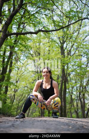 Une fille posant en position de squat pendant un entraînement dans le parc Banque D'Images