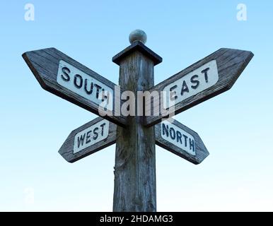 Panneau de direction en bois affichant le compas pointe vers le nord, l'est, le sud, l'ouest.Placez-vous dans un ciel bleu pâle et clair. Banque D'Images