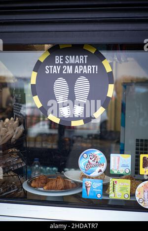 2 mètres de distance sociale conseils dans la fenêtre du kiosque du café, Goring, West Sussex Banque D'Images