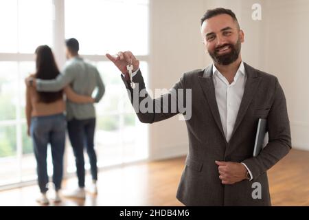 Portrait d'un agent immobilier souriant tenant et montrant la clé Banque D'Images