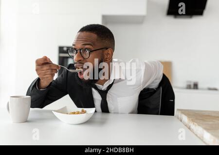 Homme noir se précipitant pour travailler manger des céréales à la maison Banque D'Images