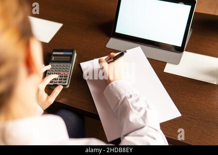 Femme écrivant et utilisant une calculatrice, utilisant une tablette numérique, femme d'affaires ou étudiant.Concept de travail à domicile Banque D'Images