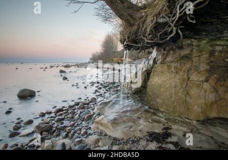 Falaise côtière et cascade pittoresques sur fond de couleur coucher de soleil Banque D'Images