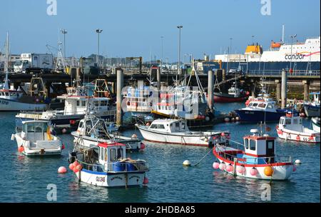 De petits bateaux de pêche colorés amarrés dans un port animé de St Peter Port, Guernesey, îles Anglo-Normandes. Banque D'Images