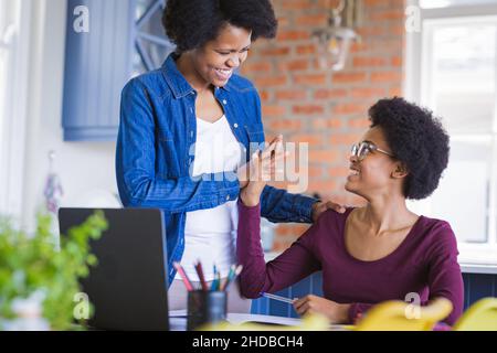 Une mère heureuse donne cinq à sa fille étudiant pendant une conférence en ligne à la maison Banque D'Images