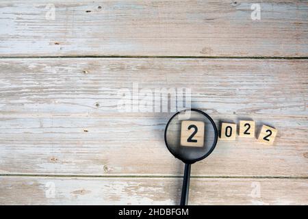 cubes en bois avec le texte 2022 avec loupe sur fond en bois vue du dessus, espace de copie conception moderne, concept du nouvel an Banque D'Images