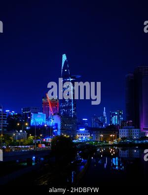 Bitexco Financial Tower brille dans des teintes bleues sur l'horizon de Saigon de l'autre côté de la rivière dans le District 3 Banque D'Images