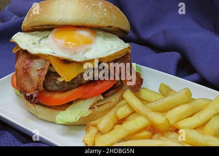 Photo d'un hamburger et d'un sandwich au bacon avec des frites sur un chiffon bleu marine Banque D'Images