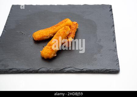 bâtonnets de poisson, sur plaque en fonte isolée sur fond blanc Banque D'Images