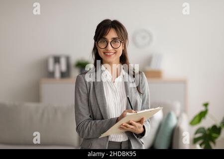 Bonne professionnelle moyenne-orientale femme psychologue regardant et souriant à la caméra, travaillant dans un bureau moderne Banque D'Images