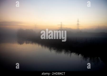 Wilhelmshaven, Allemagne.21st décembre 2021.Un épais brouillard surplombe la rivière Maade dans le quartier d'Heppenser Groden peu avant le lever du soleil.Credit: Hauke-Christian Dittrich/dpa/Alay Live News Banque D'Images