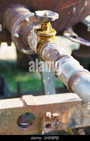 Robinet d'un réservoir d'eau ouvert .Des gouttes tombent du tuyau.Environnement rustique Banque D'Images