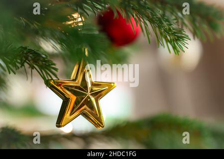 Magnifique décoration de Noël suspendue sur un arbre vert.Décoration de saison de l'étoile dorée. Banque D'Images