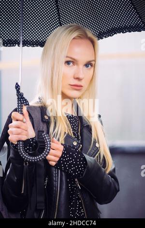 Blond aux yeux bleus avec parapluie dans la rue Banque D'Images