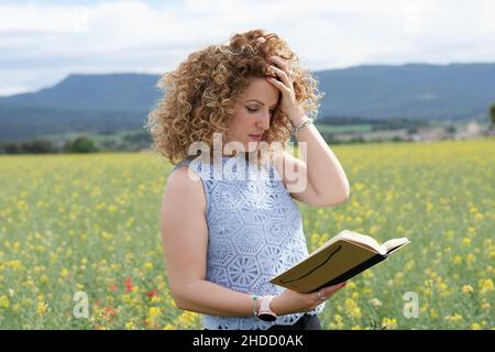 Fille aux cheveux blonds, pensant la manière et avec une main sur sa tête et l'autre tenant le bloc-notes. Banque D'Images