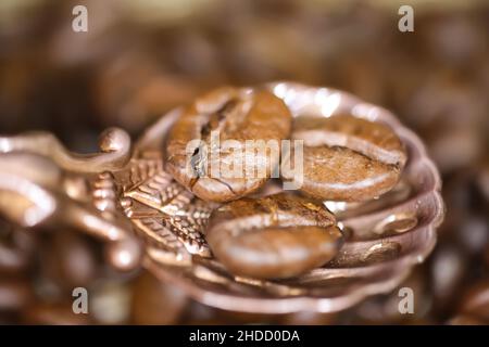 Macro gros plan de cuillère en bronze vintage avec trois grains de café rôtis, fond flou Banque D'Images