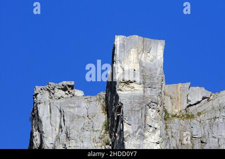 Preikestolen (rocher de Pulpit). 604 mètres / 1982 pieds au-dessus de Lysefjord. Les gens peuvent être vus assis sur le bord du toit plat de 25m x 25m. Banque D'Images