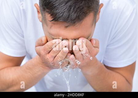 Portrait d'un jeune homme se lavant le visage avec une éclaboussure d'eau le matin Banque D'Images