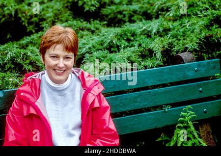 Femme mûre souriante assise sur le banc du parc avec espace de copie Banque D'Images