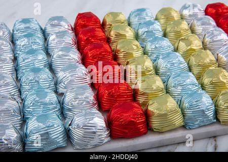 Boules de chocolat rondes avec papier d'emballage en aluminium dans un récipient en boîte sur fond de marbre.Composition minimaliste de printemps festif.Mise au point sélective douce, Banque D'Images