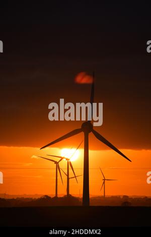 Un coucher de soleil enflammé derrière les éoliennes britanniques géantes Banque D'Images