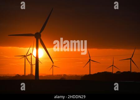 Un coucher de soleil enflammé derrière les éoliennes britanniques géantes Banque D'Images