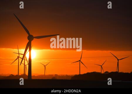 Un coucher de soleil enflammé derrière les éoliennes britanniques géantes Banque D'Images