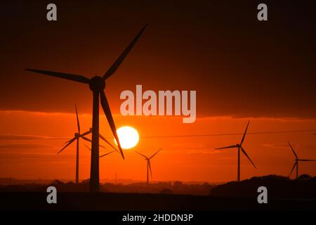 Un coucher de soleil enflammé derrière les éoliennes britanniques géantes Banque D'Images