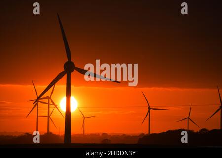 Un coucher de soleil enflammé derrière les éoliennes britanniques géantes Banque D'Images