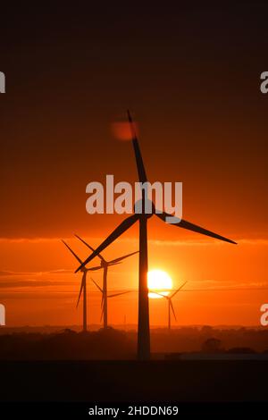 Un coucher de soleil enflammé derrière les éoliennes britanniques géantes Banque D'Images