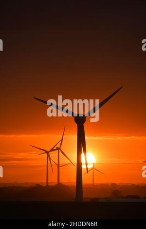 Un coucher de soleil enflammé derrière les éoliennes britanniques géantes Banque D'Images