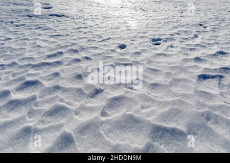 La neige ondulée par le vent crée de petits reliefs à la surface du sol dans les montagnes.Arrière-plan avec texture. Banque D'Images