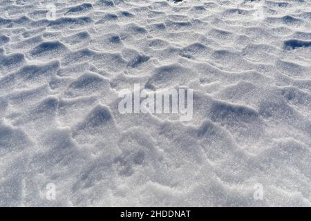 La neige ondulée par le vent crée de petits reliefs à la surface du sol dans les montagnes.Arrière-plan avec texture. Banque D'Images