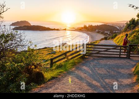 Tauranga Nouvelle-Zélande - janvier 2 2022 ; ombres de la porte sur le chemin lorsque l'homme arrive sur le Mont à pied au lever du soleil. Banque D'Images