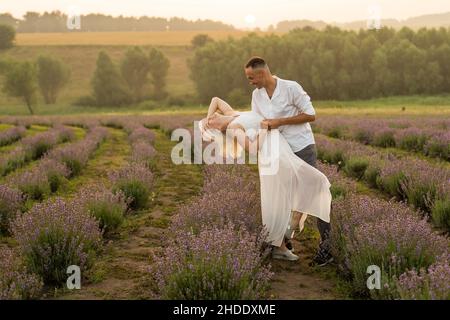 Un couple aimant debout dans un champ de lavande et embrassant Banque D'Images