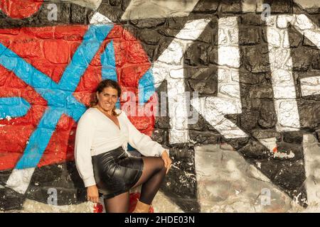 Femme caucasienne posant devant un mur de graffiti coloré Banque D'Images