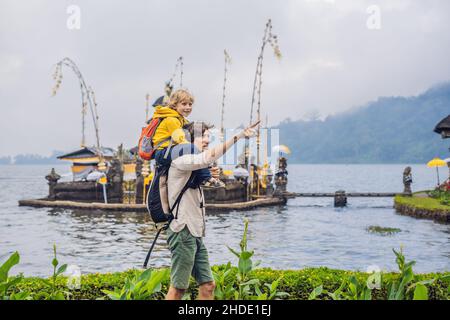 Père et fils dans l'arrière-plan de Pura Ulun Danu Bratan, Bali. Hindu Temple entouré de fleurs sur le lac Bratan, Bali. Temple de l'eau dans les grands Shivaite Banque D'Images